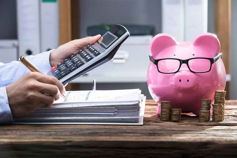 Hände mit Aktenordner, Taschenrechner und Sparschwein