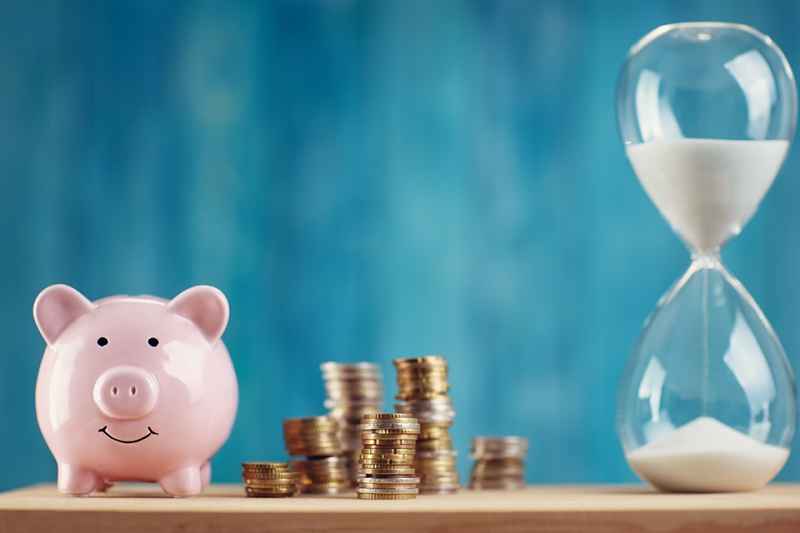 Sparschwein mit Münzen und Sanduhr